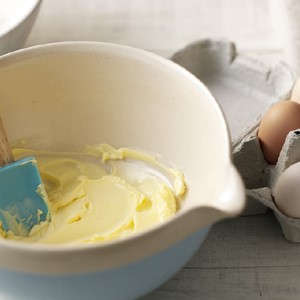 A bowl filled with cake batter with eggs to the side.