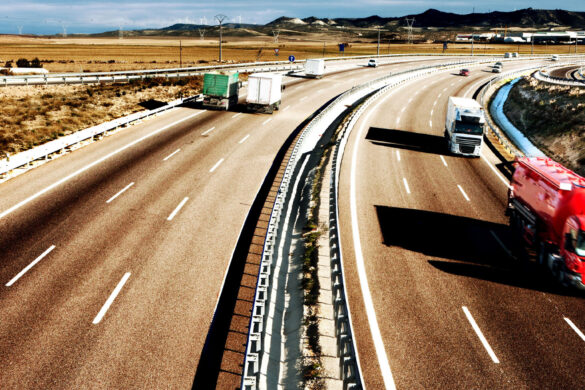 Several large trucks on a multi-lane highway.