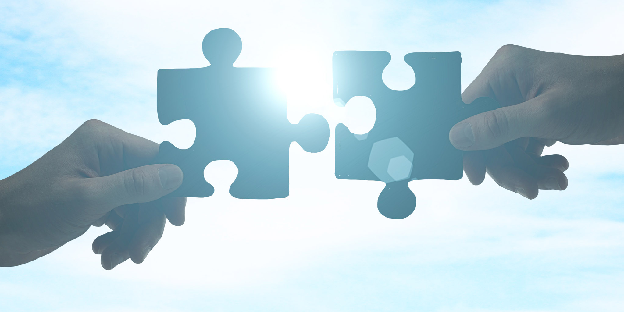 Two people holding interlocking puzzle pieces.