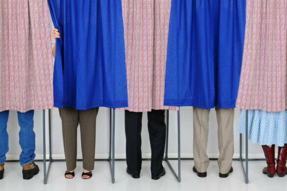 People using voting booths with curtains.