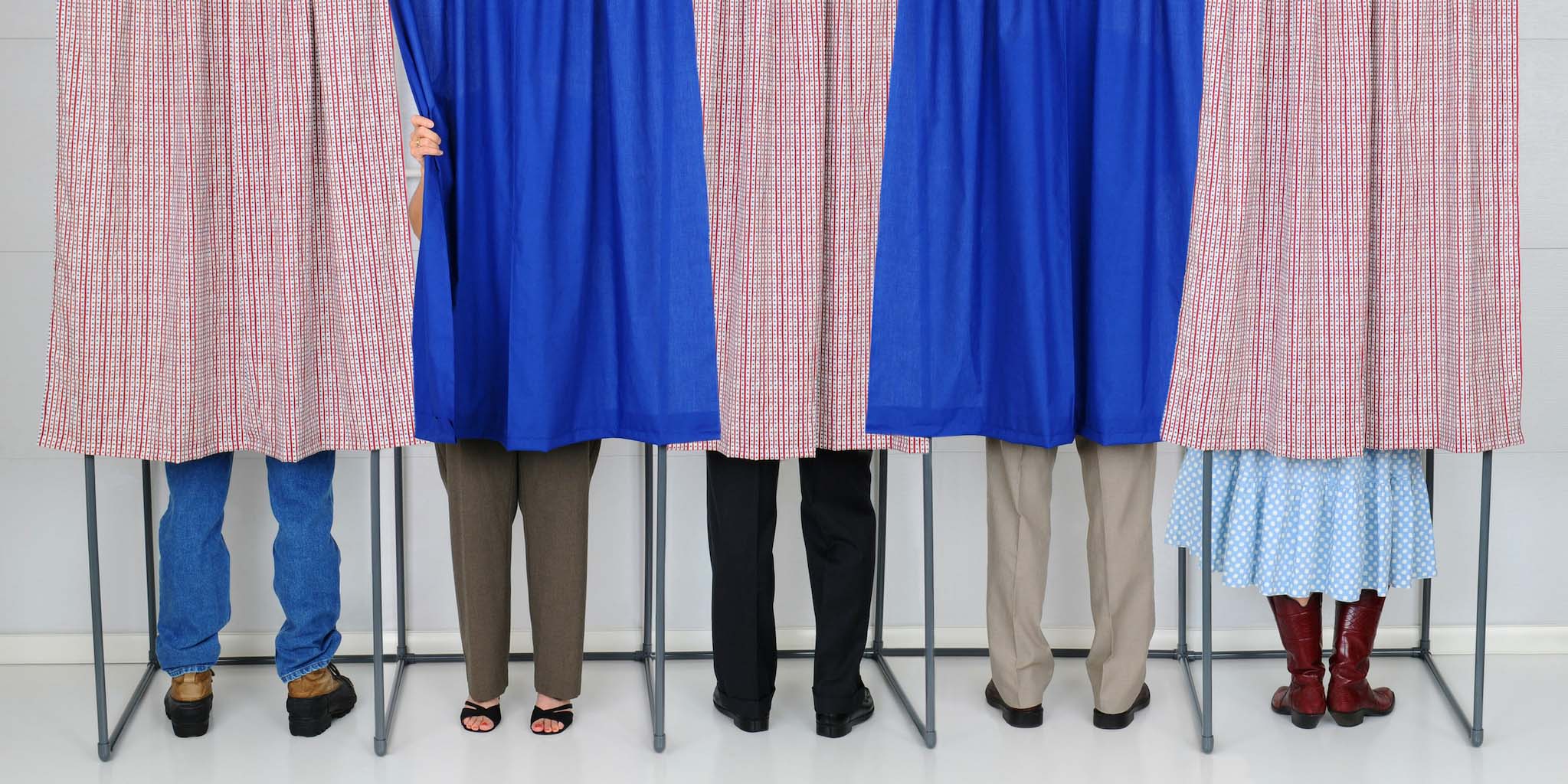 People using voting booths with curtains.