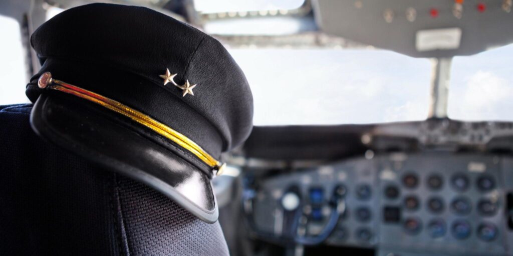Aviator hat resting on the pilots seat in an airplane.